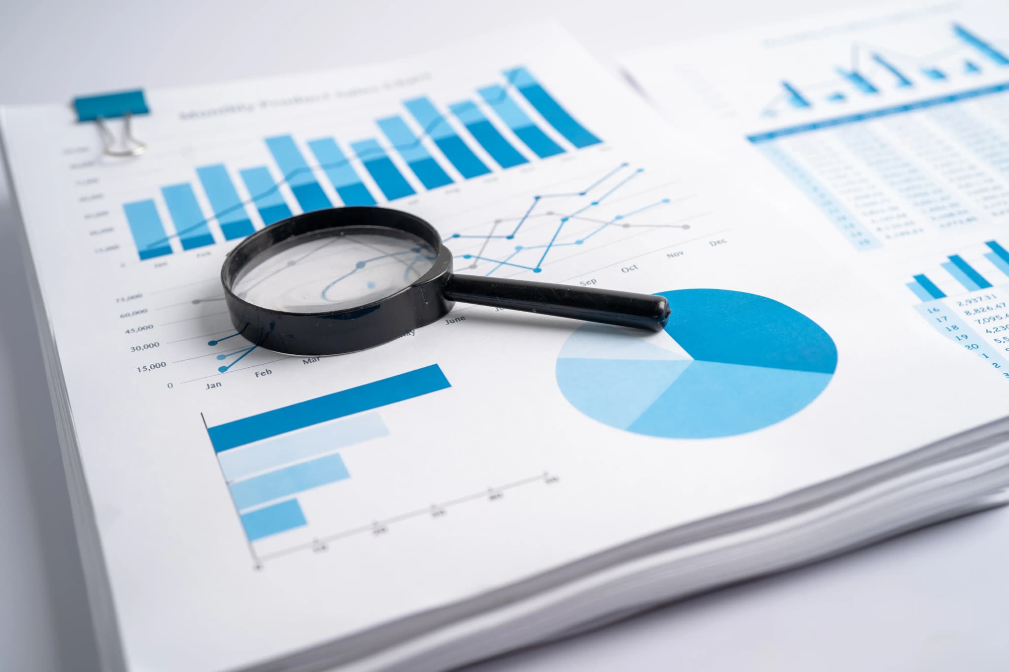 A magnifying glass held over a printed bar chart