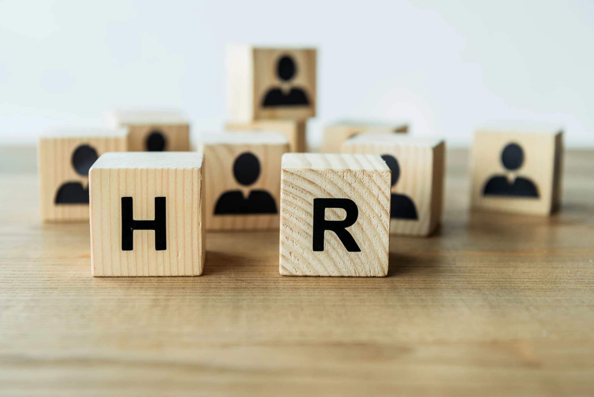 Wooden cubes spelling the letters H and R on a desk